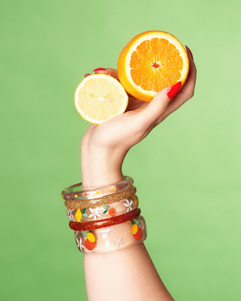 Splendette vintage inspired 1940s style orange and yellow fakelite Citrus jewellery with hand model holding oranges and lemons