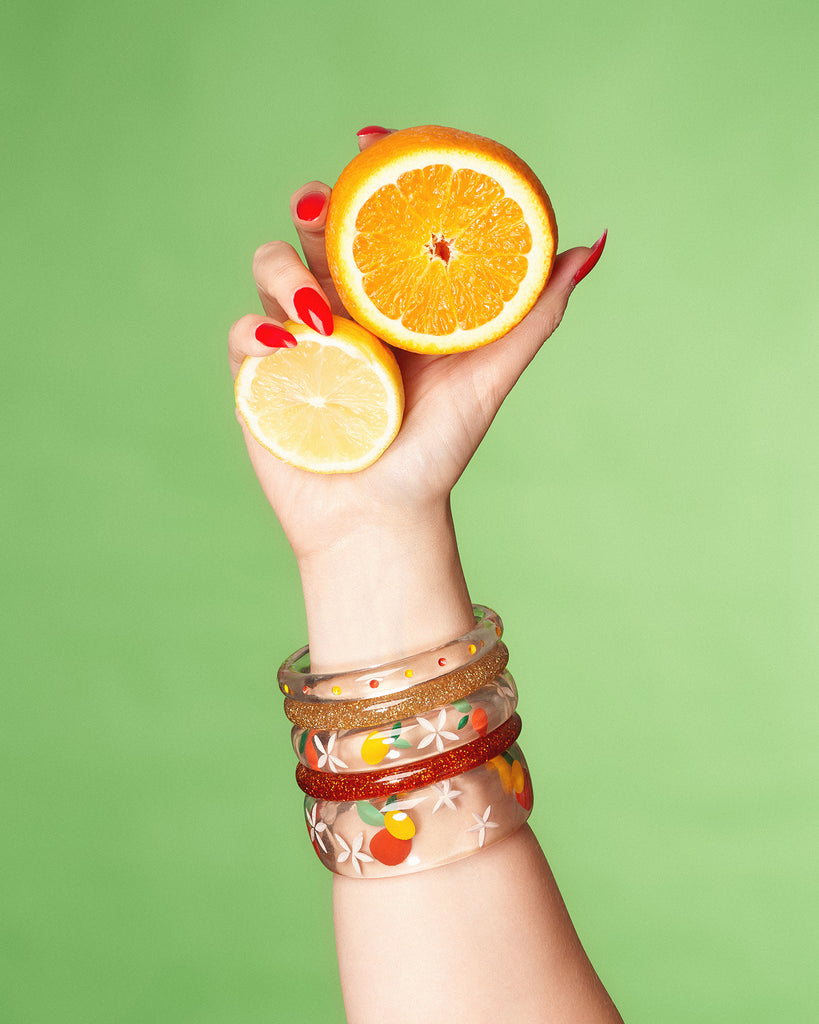 Splendette vintage inspired 1940s style orange and yellow fakelite Citrus jewellery with hand model holding oranges and lemons