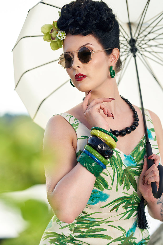 Splendette vintage inspired 1940s style model wearing heavy carved Bakelite style fakelite jewellery in green, blue and black, featuring Forest and Chartreuse bangles