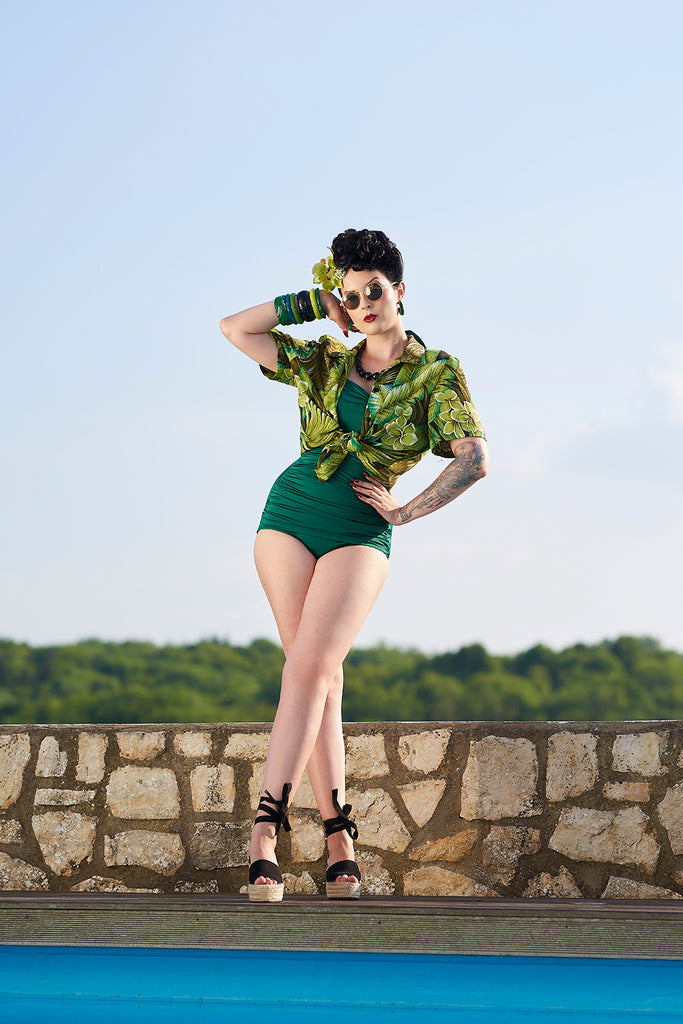 Splendette vintage inspired 1940s style pin up model wearing fakelite jewellery and green swimsuit by a pool