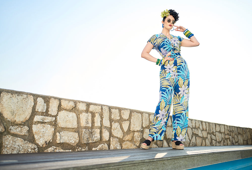 Splendette vintage inspired 1940s style pin up model wearing fakelite jewellery and blue tropical outfit by a pool
