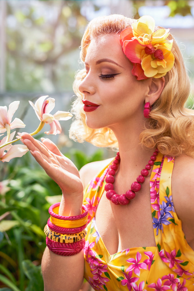 Splendette vintage inspired 1950s pin up model wearing Iris Pink heavy carve fakelite jewellery in a tropical setting