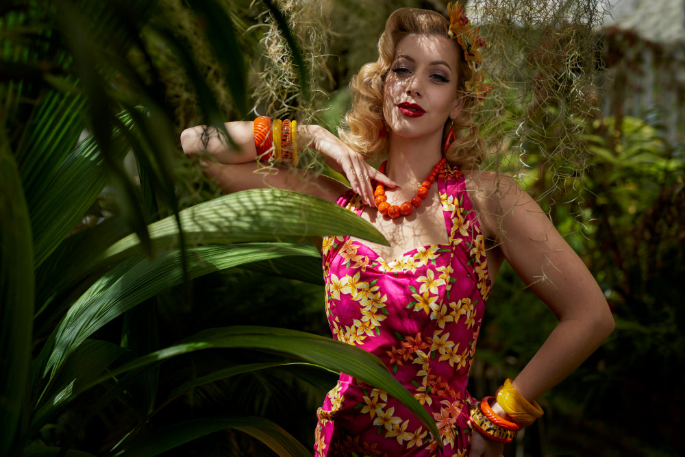 Splendette vintage inspired 1950s style model wearing orange Papaya and yellow Yolk fakelite jewellery in a tropical setting