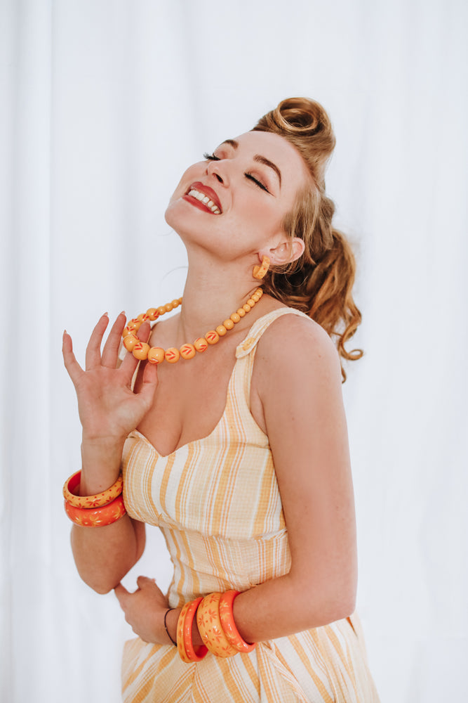 Splendette vintage inspired 1950s pin up style yellow and peachy orange carved Duotone Spring 2021 jewellery worn by Blossom & Buttercups