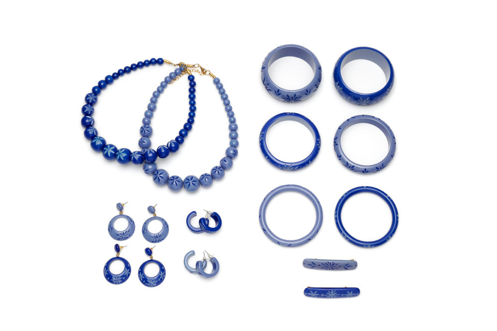 Splendette vintage inspired 1950s style Spring 2021 blue carved Duotone fakelite jewellery flat lay with Cornflower and Forget-Me-Not bangles, bead necklaces, hoop and drop earrings, and hair barrettes
