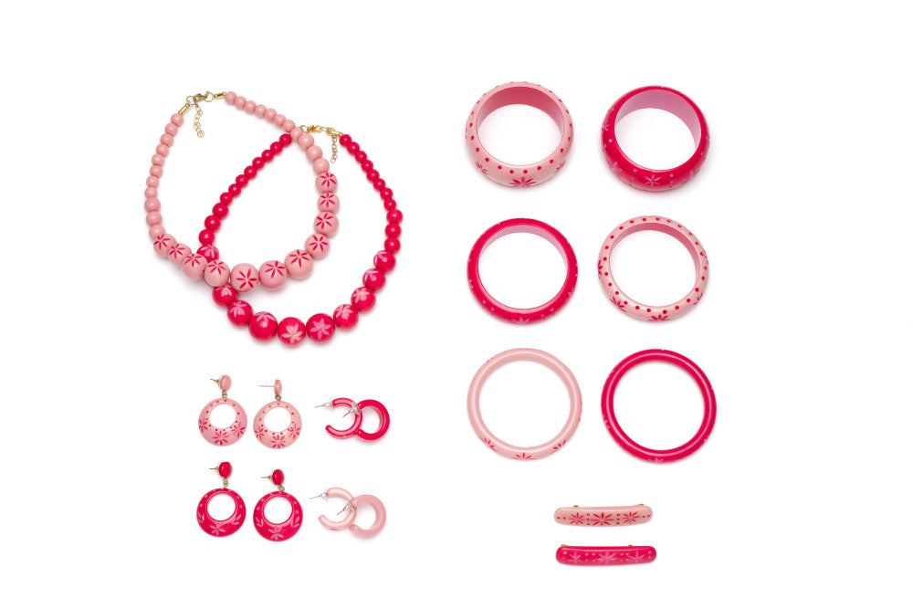 Splendette vintage inspired 1950s pin up style soft pink and bright pink carved Duotone fakelite jewellery flat lay with bangles, earrings, necklaces and hair barrettes