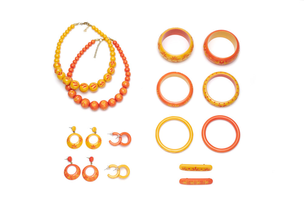 Splendette vintage inspired 1950s Bakelite style peachy orange and yellow carved Duotone fakelite jewellery flat lay with bangles, bead necklaces, earrings and hair barrettes