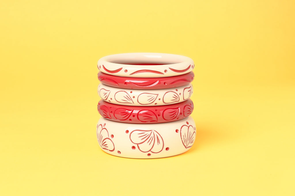 Splendette vintage inspired 1940s style carved coral pink fakelite Petal and Petal Cream Bangles on a yellow background