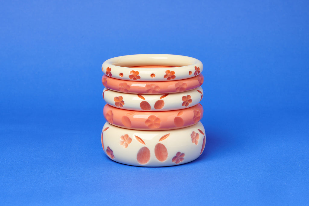 Splendette vintage inspired 1940s style carved peachy orange fakelite Apricot and Apricot Cream Bangles on a blue background